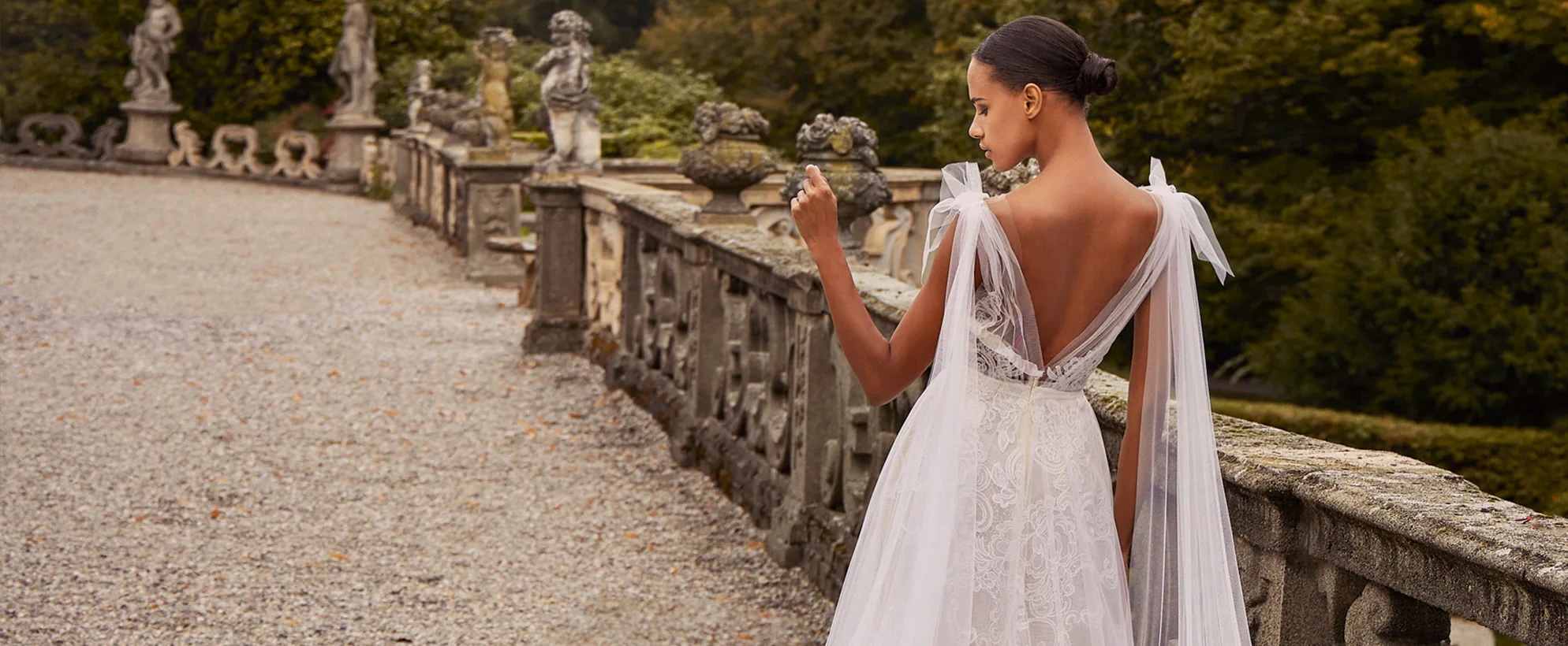 A model wears an Ines Di Santo dress while crossing a stone bridge