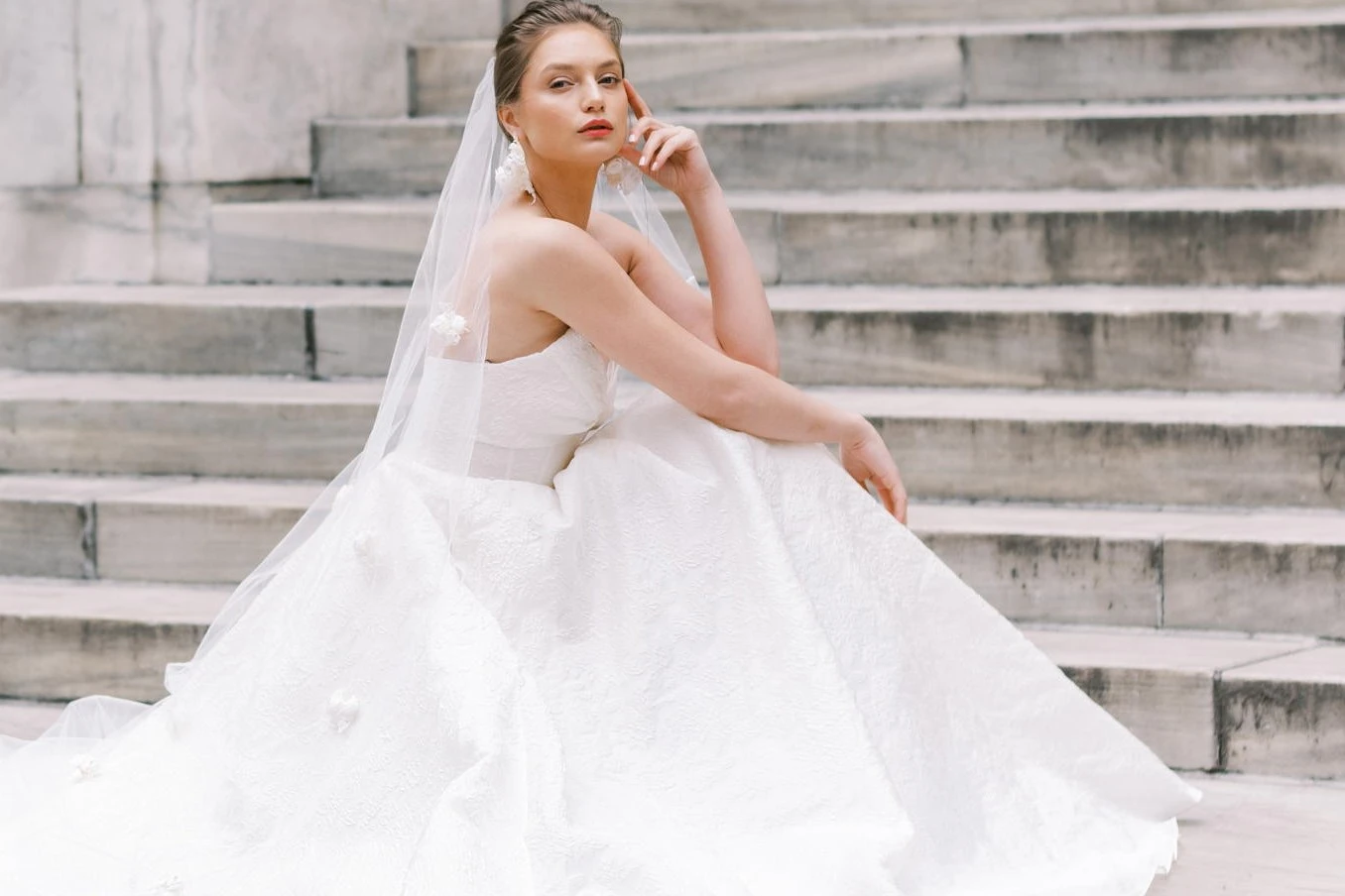 A model wears a dress by Atelier Beccar on the steps of a large building