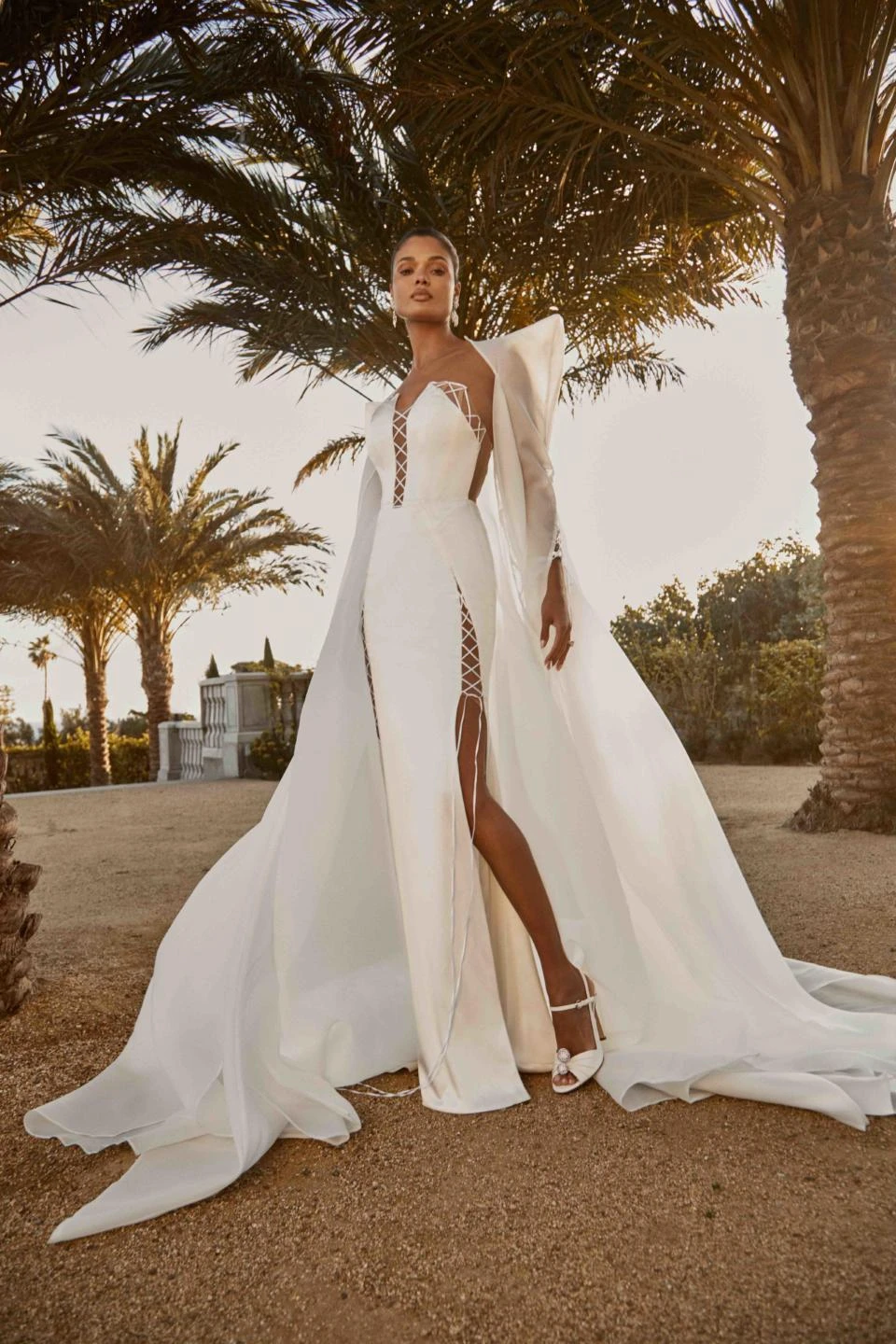 A model wears the Galia Lahav Aspen dress at sunset near palm trees