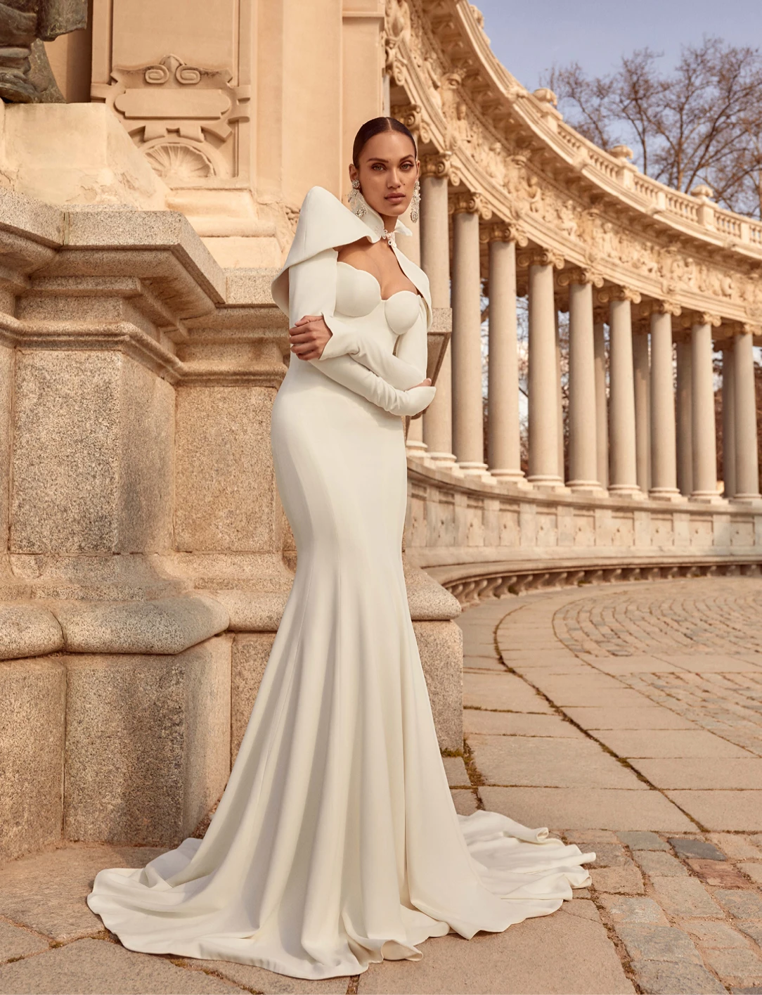 A model wears the Galia Lahav Paloma dress outside near a stone building