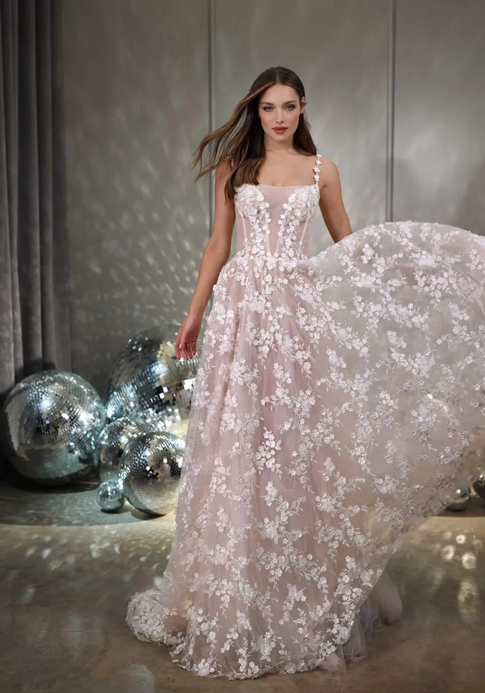 A model wears the Galia Lahav Twinkle dress in a room with large disco balls