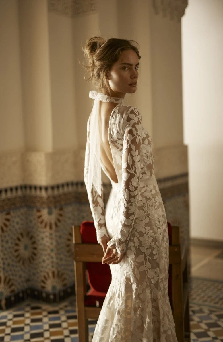 A model wears the Arava Polak Brigitte dress while standing inside of an old building