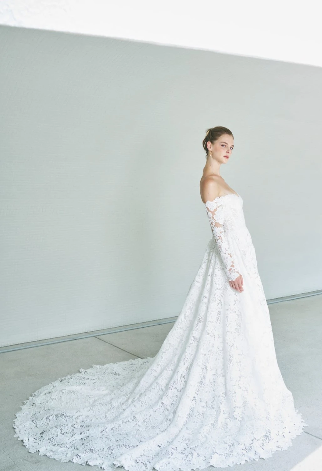 A model wears the Atelier Beccar Shanti dress in a photography studio with blue/grey backdrop