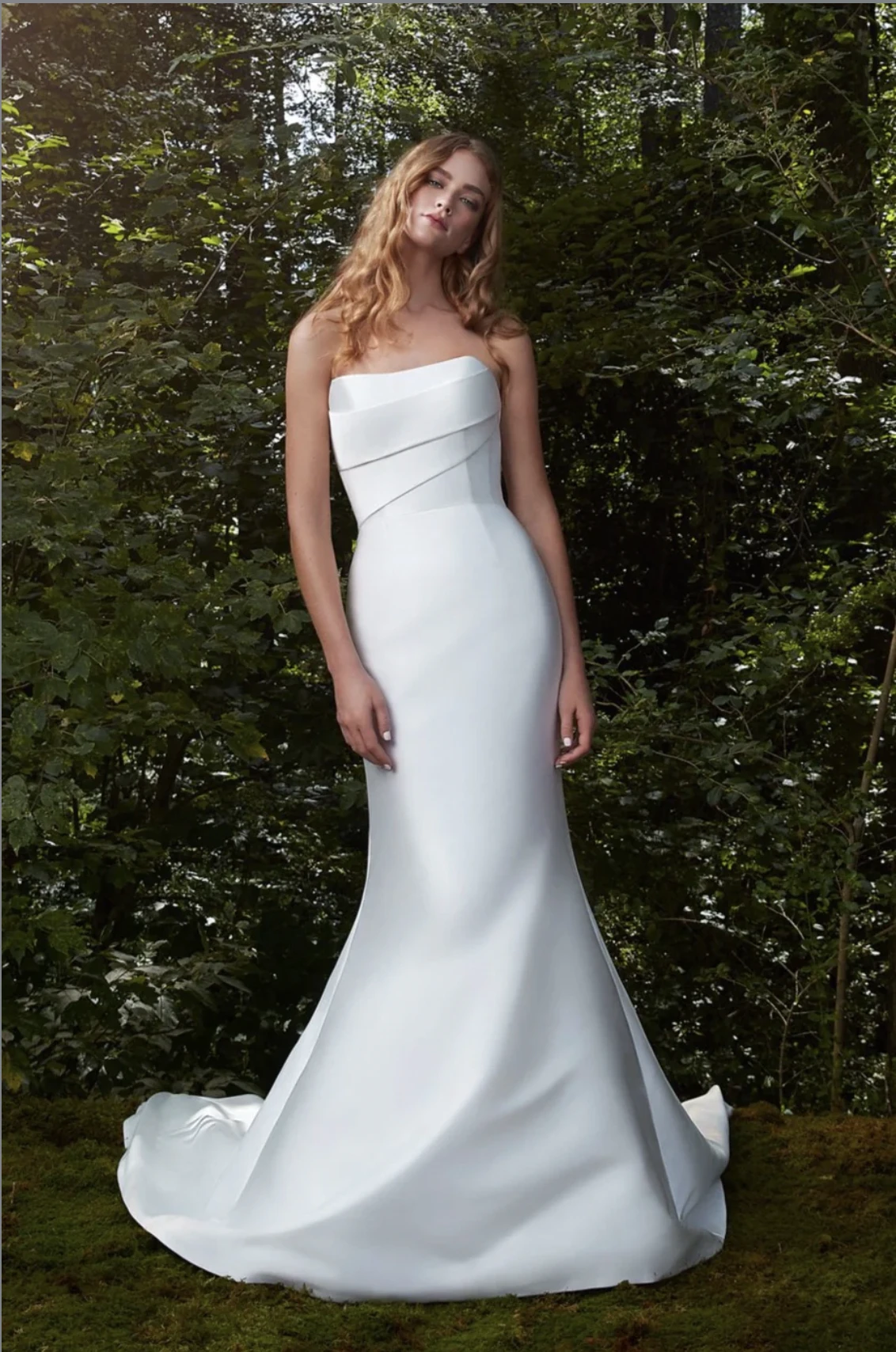 A model wears the Anne Barge Bisous dress while standing next to green foliage