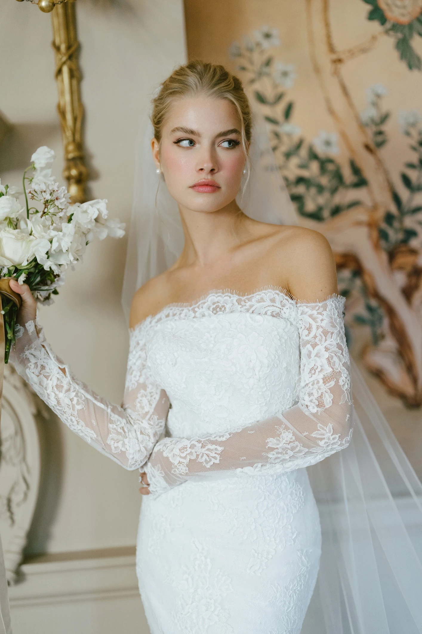 A model wears the Anne Barge Collier dress while holding a bouquet of flowers