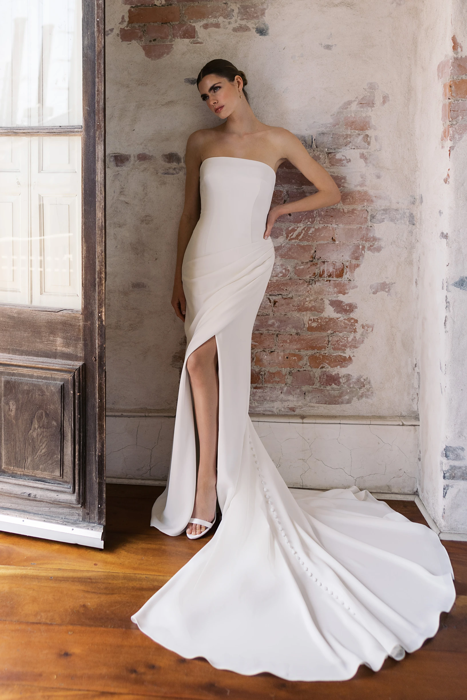 A model wears the Anne Barge Conti dress near a brick wall and doorway