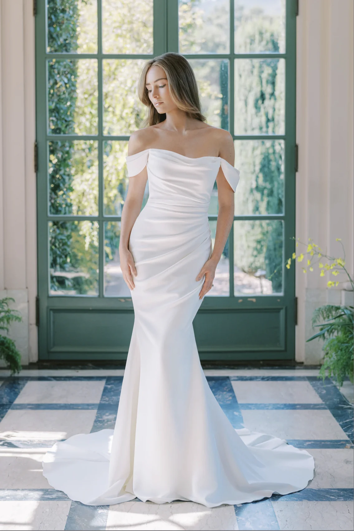 A model wears the Anne Barge Naomi dress in front of a glass doorway