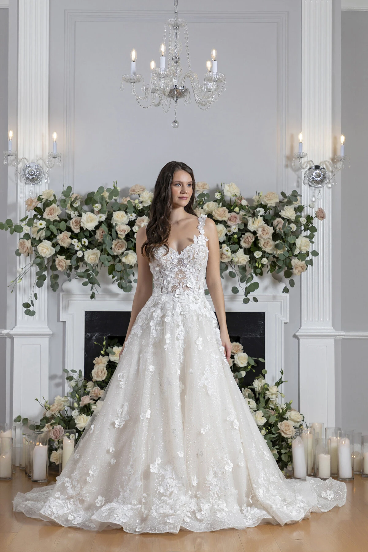 A model wears the Angel Rivera Garden In Bloom dress in front of a fireplace with flowers