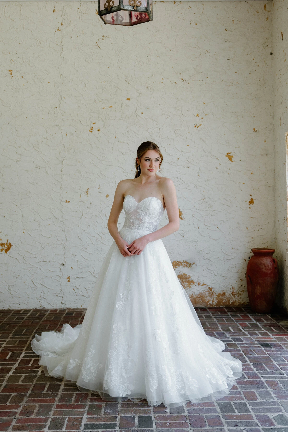 A model wears the Angel Rivera Marigold dress in a room with old plaster walls