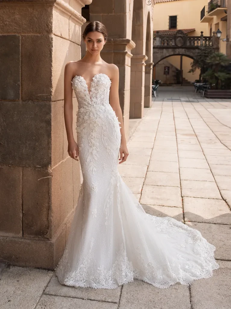 A model wears the Pronovias Aethra dress near a stone wall