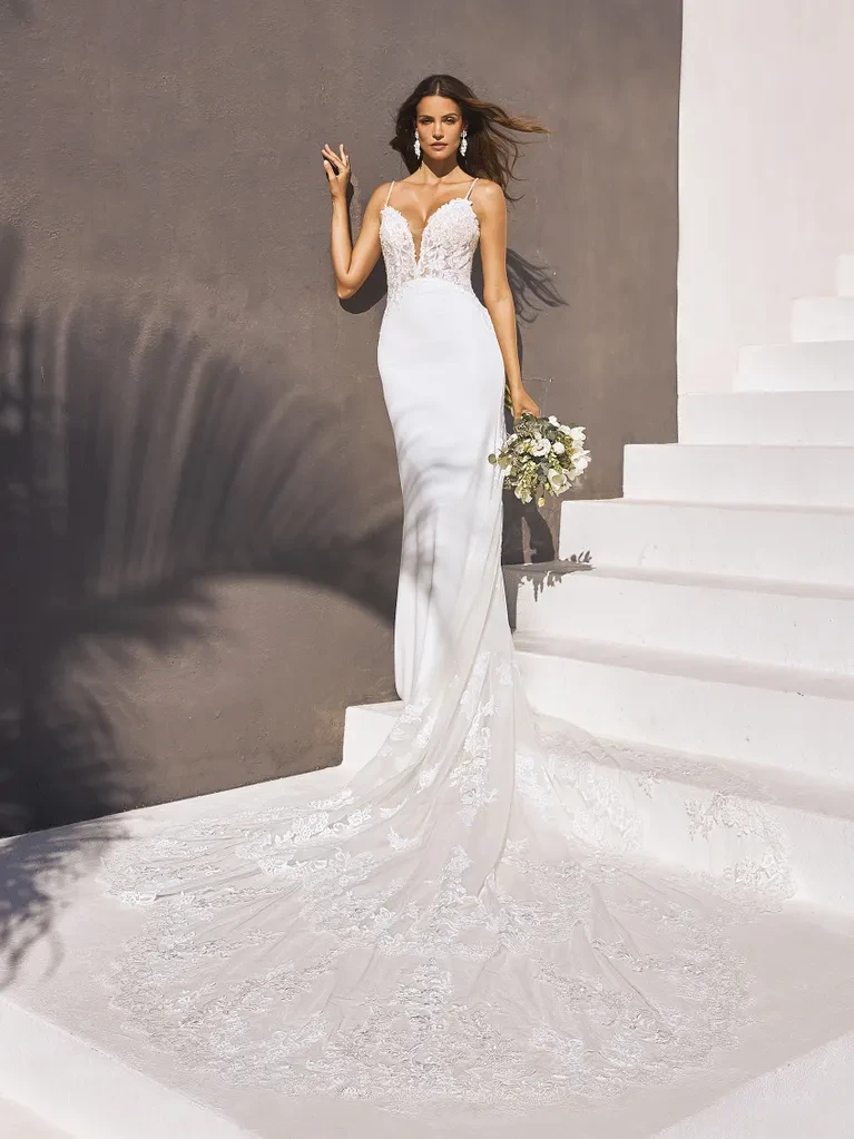 A model wears the Pronovias Izara dress while standing on white outdoor stairs