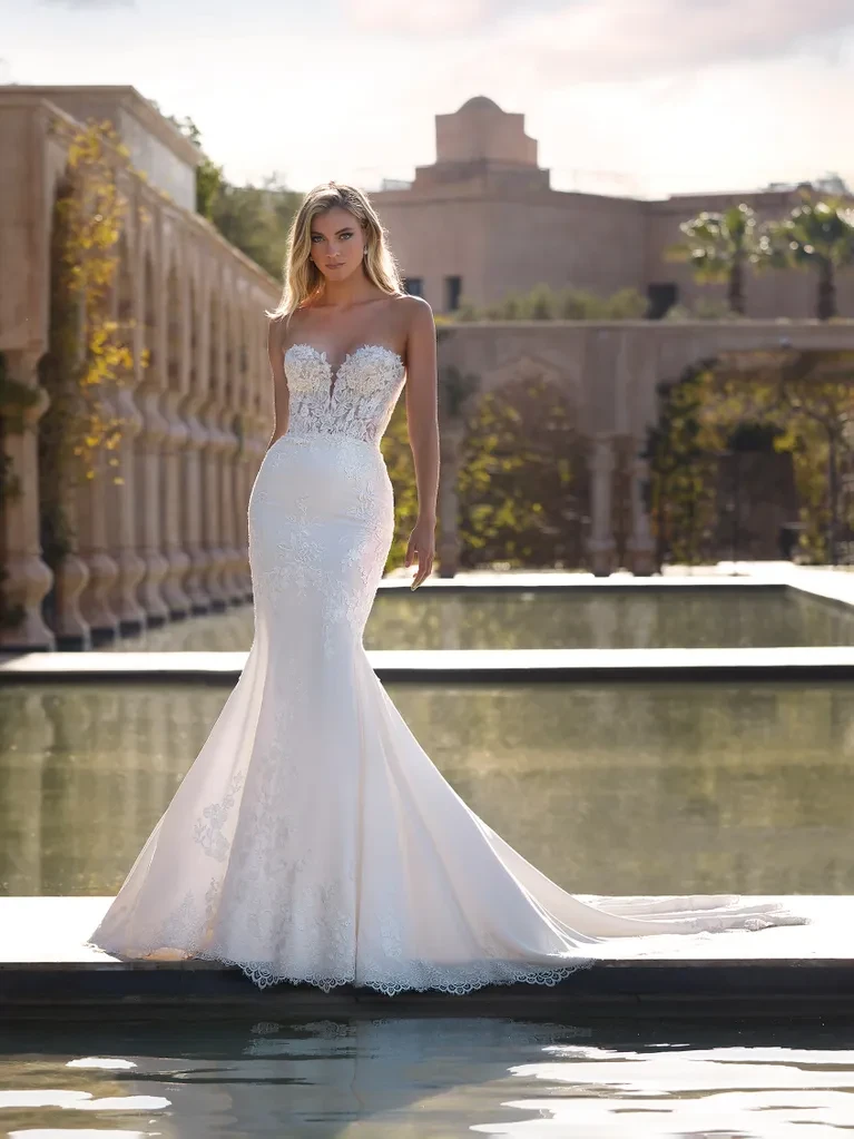 A model wears the Pronovias Kodiak dress while standing near an outdoor pond